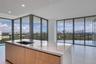 Kitchen island featuring waterfall-edge stone countertops, undermount sink, gooseneck faucet, and wood-finish cabinetry, set against floor-to-ceiling 