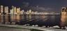 Waterfront property featuring a stone-paved promenade, natural rock bulkhead, and skyline backdrop