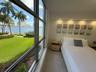 Floor-to-ceiling windows, recessed lighting, and water-facing scenery featuring manicured landscaping and palms