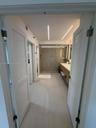Bathroom featuring dual louvered doors, recessed linear ceiling lighting, floating wood-finish vanity with countertop, and a walk-in glass-enclosed sh