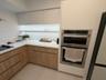 Kitchen featuring two-tone cabinetry with wood-finish lower units, white upper cabinets, white solid-surface countertops, integrated under-cabinet lig