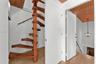 Custom wooden spiral staircase with central support post, wood-finish flooring, planked wood ceilings, and geometric metal pendant lighting