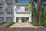 Stucco exterior featuring a second-story balcony with metal railing, a paved driveway, and an attached multi-purpose garage