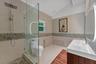 Bathroom featuring a glass-enclosed shower with pebble stone flooring and wall accents, a wood-finish vanity with a rectangular sink, wall-mounted ill