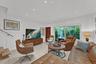 Large-format tile flooring, recessed ceiling lighting, sliding glass door with exterior access, and a floating wood-tread staircase with a glass panel