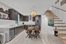 Custom cabinetry with horizontal hardware, light-toned stone tile flooring, stainless steel integrated refrigeration, stone-surfaced countertops, and 