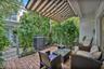 Outdoor patio featuring a herringbone-patterned brick floor, retractable striped awning, and metal perimeter fencing