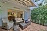 Patio featuring a herringbone-patterned brick surface, a retractable striped awning, and a sliding glass door entry