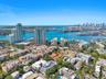 Aerial perspective of a coastal urban landscape featuring high-rise buildings, expansive harbor waterways, boat slips, and mature tropical greenery