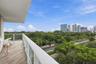 Private balcony with wood-finish flooring, glass railing, and expansive city skyline backdrop