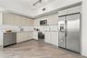 Kitchen featuring flat-panel cabinetry, light-toned countertops, stainless steel appliances, and plank-style flooring with integrated track lighting
