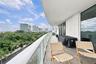 Spacious covered balcony featuring wood-finish tile flooring, glass panel railings, and metal structural supports