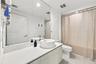 Modern floating vanity with a light wood-finish cabinet, rectangular surface-mounted sink, and wide-format wall mirror featuring a polished chrome fau