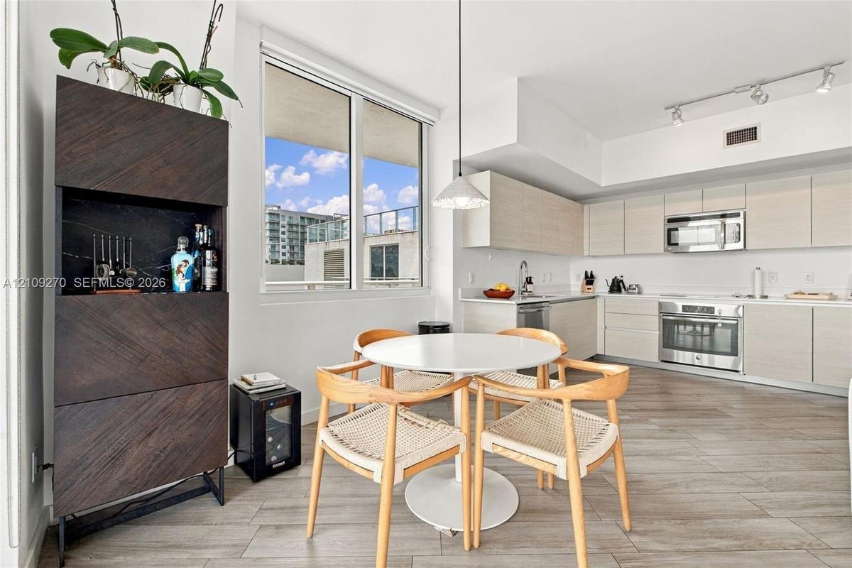 Modern kitchen featuring light-toned cabinetry, stainless steel appliances, wood-finish flooring, and track lighting