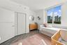 Floor-to-ceiling window with urban skyline backdrop, wood-finish flooring, and multi-panel reach-in closet with integrated door hardware
