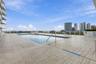Rooftop swimming pool featuring tiled decking, metal perimeter railings, and a horizontal cityscape backdrop