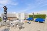 Rooftop terrace featuring light-toned tile flooring, integrated perimeter hedge, stucco wall finishes, and built-in outdoor kitchen structure with att