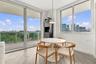 Floor-to-ceiling windows, wood-finish tile flooring, recessed balcony with glass railing, and a pendant light fixture