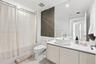 Bathroom featuring a vanity with wood-finish cabinetry, a white countertop, and a vessel sink, accompanied by a full-wall mirror, tiled flooring, and 