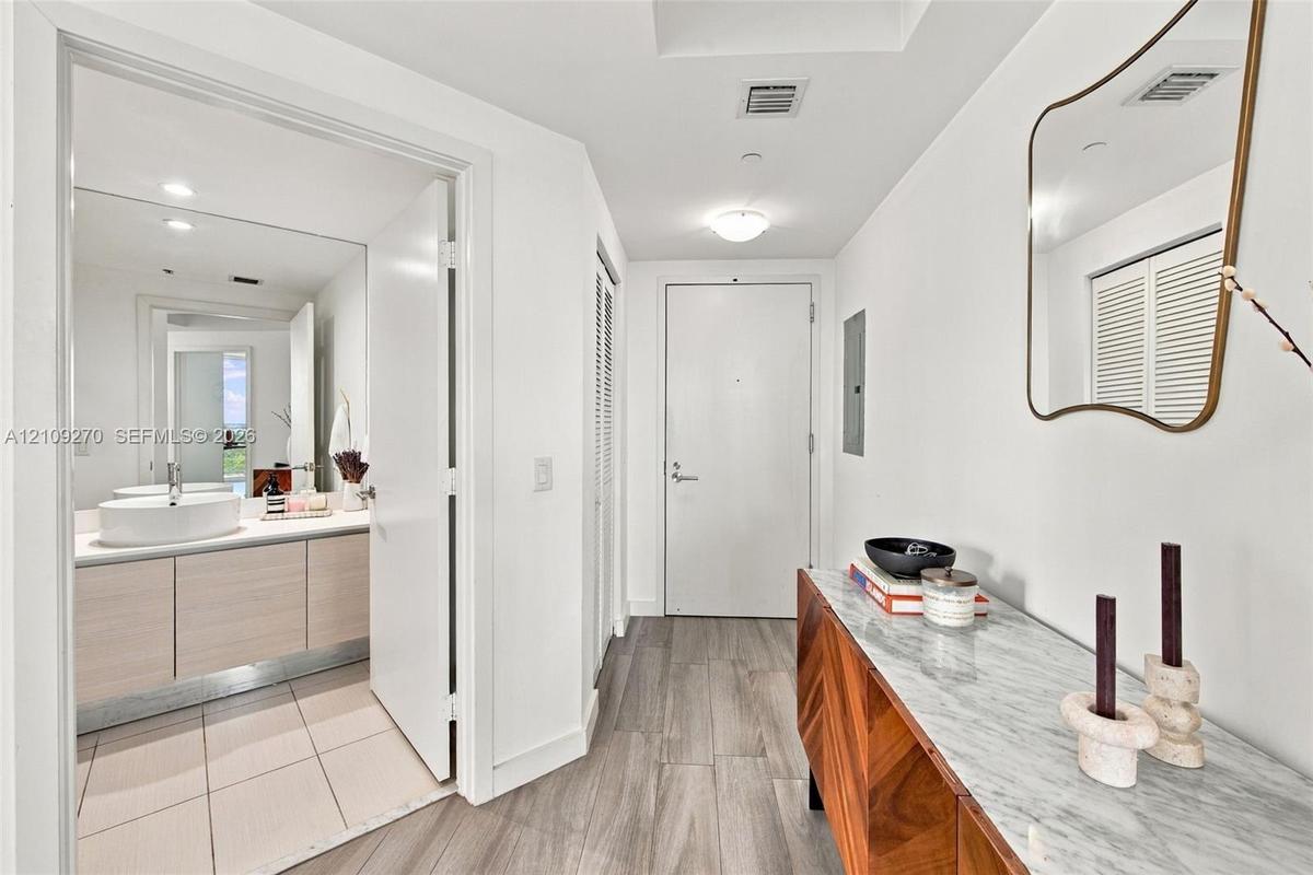 Entryway featuring wood-finish flooring, a wall-mounted mirror, and louvered closet doors