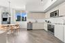 Kitchen featuring light-toned cabinetry, stainless steel appliances, wood-finish flooring, and expansive windows