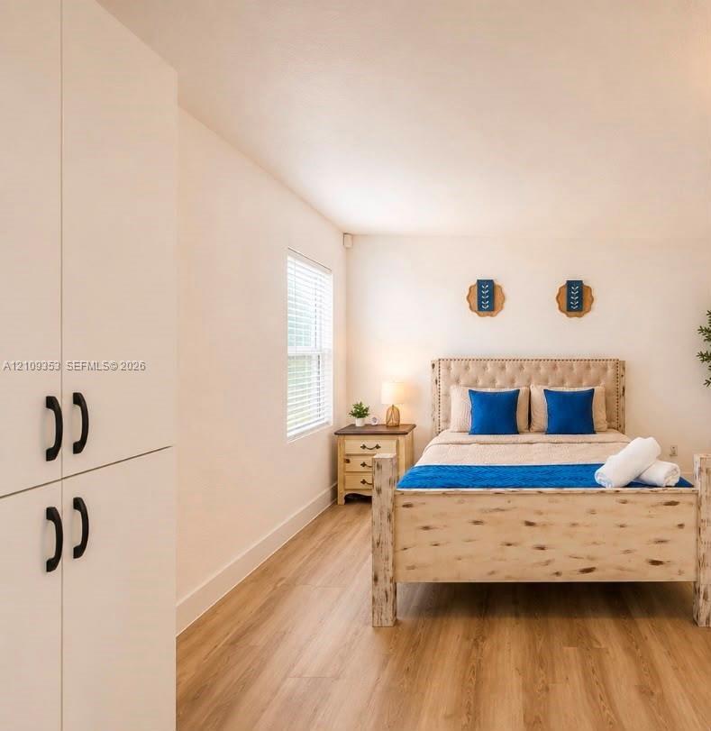 Wood-finish flooring, full-height built-in storage cabinetry with matte black hardware, and double-hung window with adjustable blinds