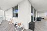 Covered balcony featuring wood-finish flooring, sliding glass door access, and white stucco walls