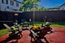 Rear patio featuring a fire pit, paved flooring, perimeter wood fencing, and mature palm trees
