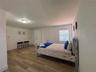 Wood-finish flooring, white-finish built-in cabinetry, and a window with horizontal blinds