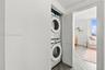 Laundry closet featuring a stackable washer and dryer unit enclosed by white louvered bi-fold doors