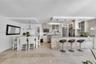 Kitchen featuring stone-finish cabinetry, stone-clad breakfast bar, stone flooring, stainless steel appliances, and tray ceilings