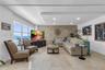 Living area featuring a textured stone accent wall, recessed ceiling lighting, neutral tile flooring, and large windows with water scenery