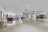 Expansive common area featuring polished stone flooring, recessed lighting, mirrored structural columns, and large windows