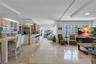 Open-concept layout featuring stone tile flooring, a kitchen island with stone cladding, and large windows