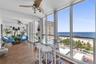 Enclosed sunroom featuring floor-to-ceiling glass panel walls, and dual ceiling fans, accented by a panoramic ocean backdrop