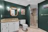 Bathroom featuring a white vanity cabinet with stone-finish countertop, undermount sink, dual wall-mounted light fixtures, and a glass-enclosed shower