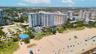 High-rise residential complex featuring direct beach access, an outdoor swimming pool, and proximity to expansive sandy shoreline
