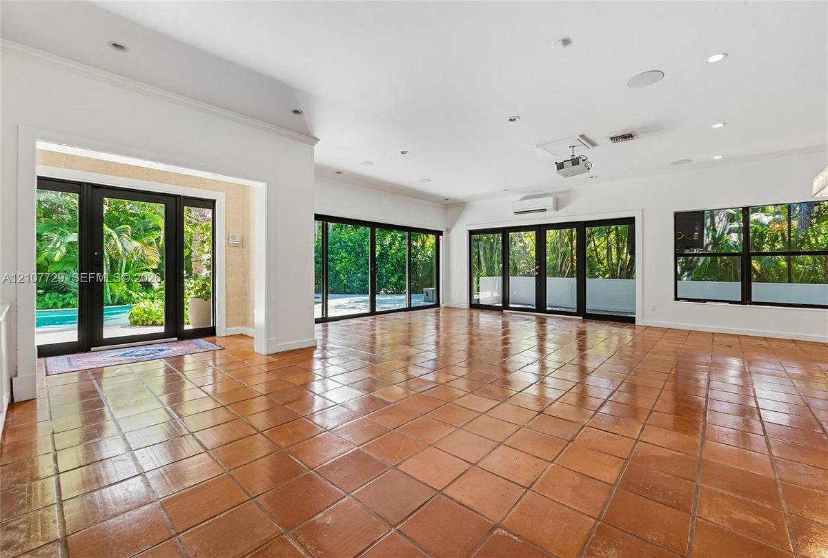 Open-concept interior featuring large-format ceramic tile flooring, multi-panel sliding glass doors, recessed lighting, and a wall-mounted climate con