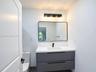 Floating vanity with matte finish charcoal cabinetry, white countertop, rectangular integrated sink, wall-mounted matte black faucet, and rectangular 