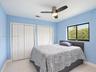 Light-filled room featuring wood-finish flooring, two sets of white bi-fold closet doors, and a brushed nickel ceiling fan with integrated lighting