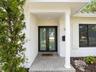 White painted brick exterior featuring a covered entryway with a column, double-glass front doors, and paved stone flooring
