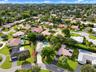 Aerial perspective of property featuring a concrete driveway, multi-paneled roof, and an in-ground swimming pool