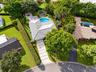 Aerial perspective featuring a tile roof, concrete paver driveway with turf accents, swimming pool, and pergola