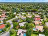 Aerial perspective of a suburban neighborhood featuring tree-lined streets, landscaped lots, and proximity to green space