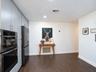 Floor-to-ceiling flat-panel cabinetry, integrated stainless steel double oven, stainless steel multi-door refrigerator, and wood-finish flooring