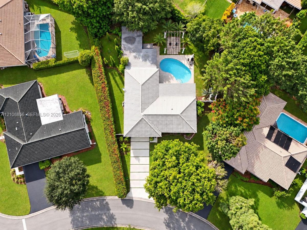 Aerial perspective featuring a concrete tile roof, curvilinear swimming pool, pergola, and a multi-section concrete paver driveway