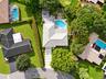 Aerial perspective featuring a concrete tile roof, curvilinear swimming pool, pergola, and a multi-section concrete paver driveway