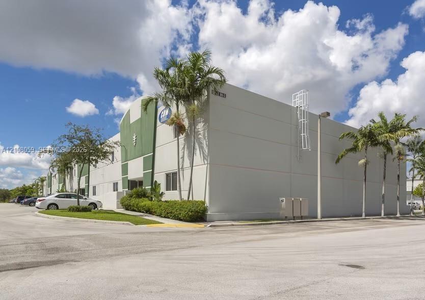 Concrete tilt-wall industrial building featuring a paved parking area, integrated roof-access ladder, and exterior landscaping
