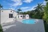 Stucco exterior residence featuring an in-ground kidney-shaped pool and expansive stone-paver patio