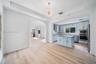 Kitchen featuring light blue cabinetry, stone countertops, stainless steel appliances, and a central island, punctuated by a tray ceiling with a conte
